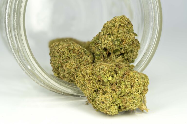 Cannabis buds spilling from glass jar.