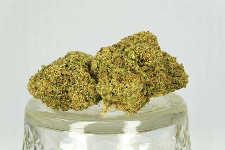 Dry cannabis buds on clear glass jar.