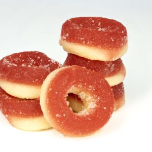 Stacked peach ring gummy candies on white background.