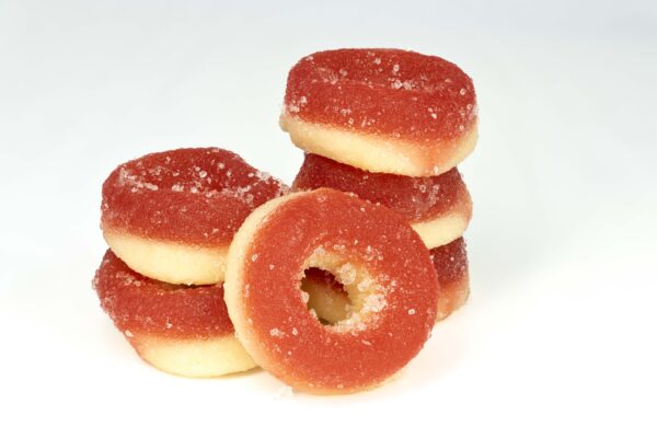 Stacked peach ring gummy candies on white background.