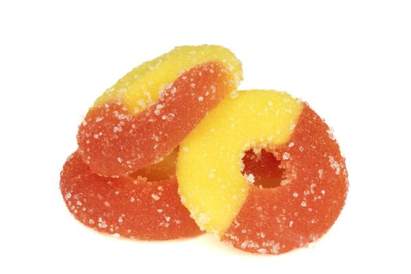 Sugar-coated peach rings candy on white background.