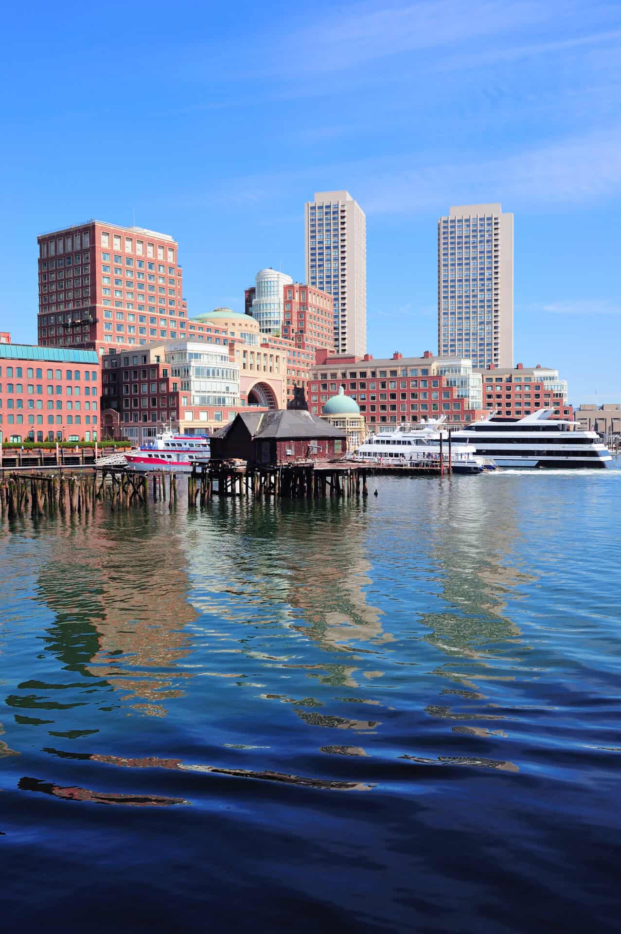 Lab-tested THCa flower shipped to Massachusetts. Boston waterfront with skyscrapers and boat in the morning.