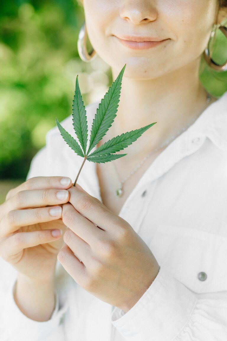 Woman holding cannabis leaf up close