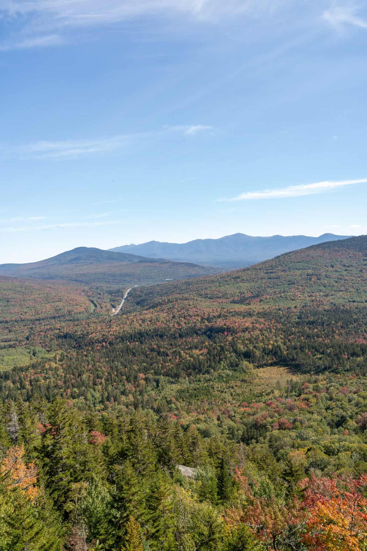Lab-tested THCa flower shipped to West Virginia. Views from atop a mountain overlooking changing trees and other mountains. High-quality photo taken in White Mountain National Forest, New Hampshire.